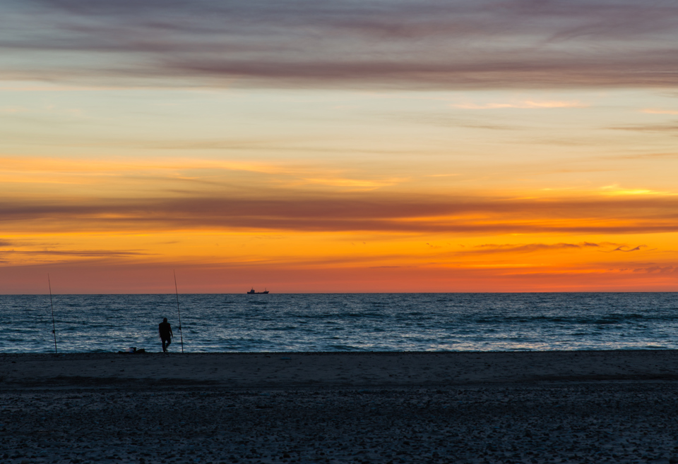 Kystfisker på strand i solnedgang